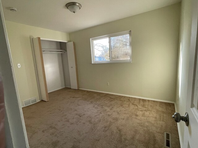 unfurnished bedroom with visible vents, baseboards, carpet, and a closet