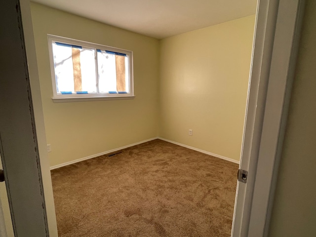 carpeted spare room featuring visible vents and baseboards