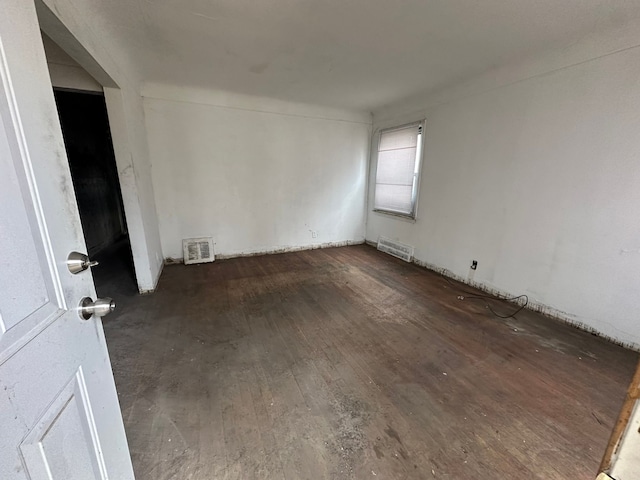 unfurnished room featuring dark wood-style flooring and visible vents