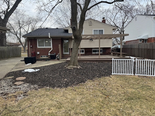 rear view of house featuring fence, a deck, and brick siding