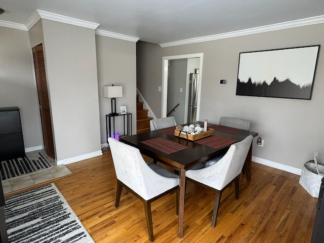 dining room with ornamental molding, stairway, wood finished floors, and baseboards