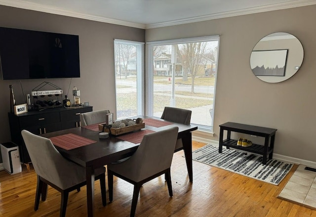 dining area featuring light wood-type flooring, crown molding, and baseboards