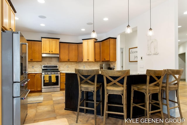 kitchen with stainless steel appliances, tasteful backsplash, a breakfast bar, and under cabinet range hood