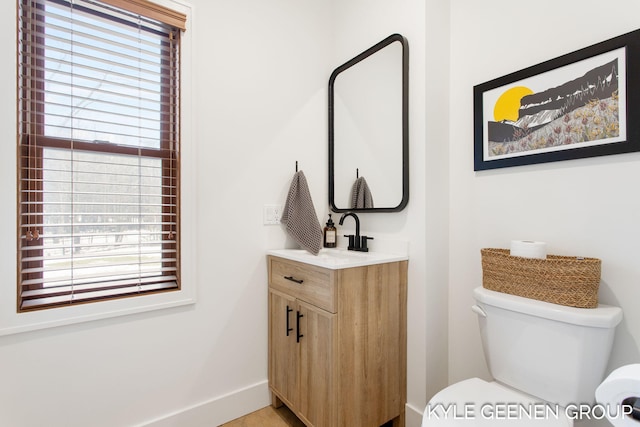 half bathroom featuring toilet, vanity, and baseboards