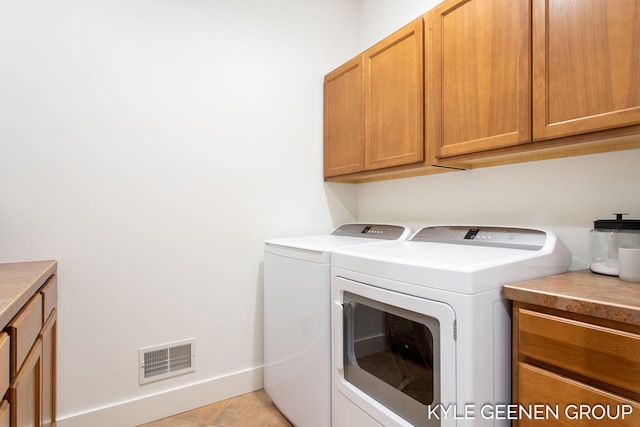 clothes washing area with washing machine and clothes dryer, cabinet space, visible vents, light tile patterned flooring, and baseboards