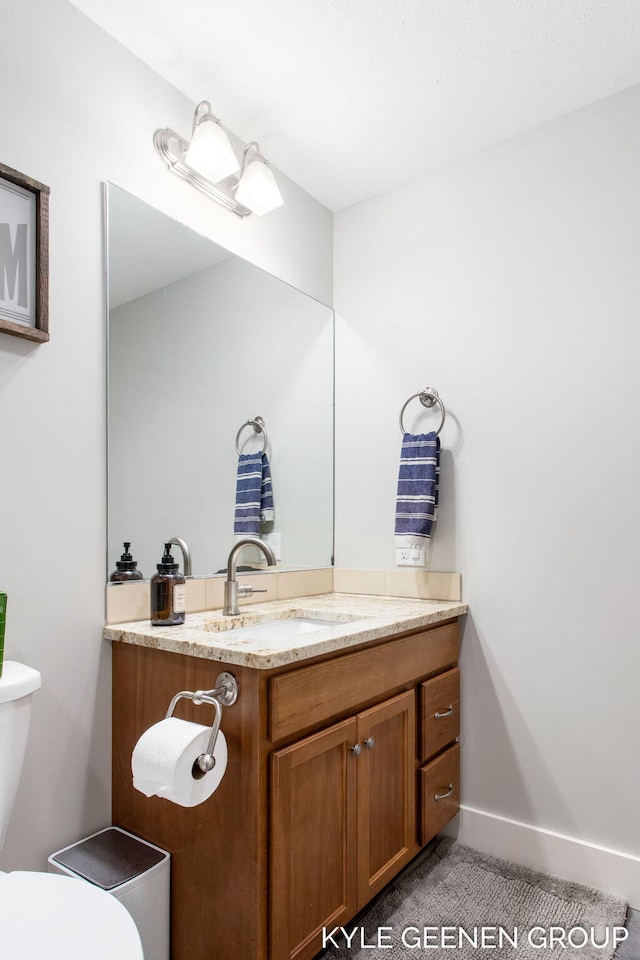 bathroom with toilet, baseboards, and vanity