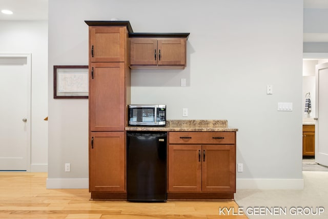 kitchen with baseboards, light wood finished floors, brown cabinetry, and refrigerator