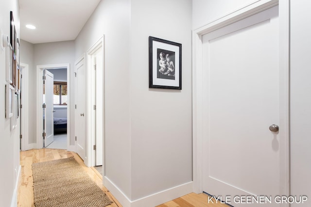 hall with recessed lighting, light wood finished floors, and baseboards