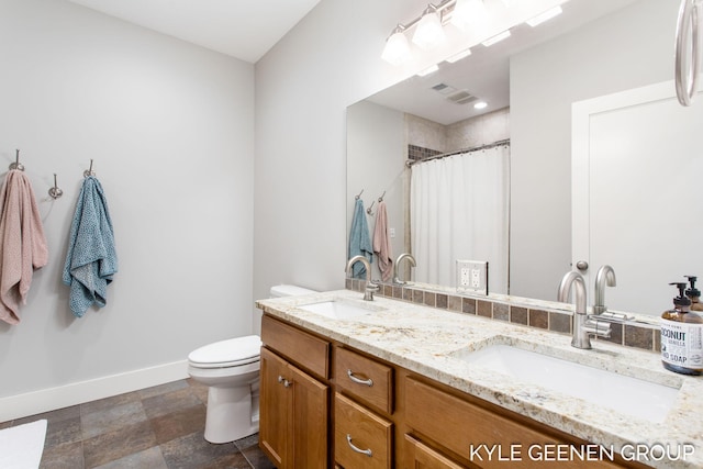 bathroom featuring toilet, a sink, visible vents, and baseboards