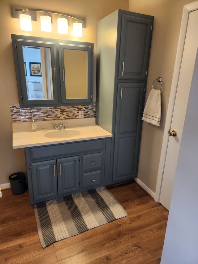 bathroom featuring baseboards, backsplash, vanity, and wood finished floors