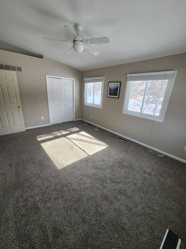 unfurnished bedroom featuring carpet, visible vents, lofted ceiling, and baseboards