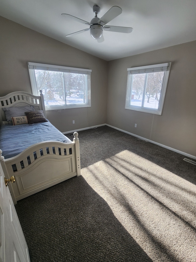 unfurnished bedroom with multiple windows, dark carpet, visible vents, and baseboards