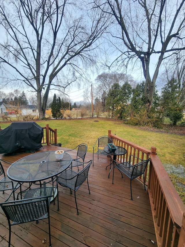 wooden terrace with outdoor dining space, a lawn, and area for grilling