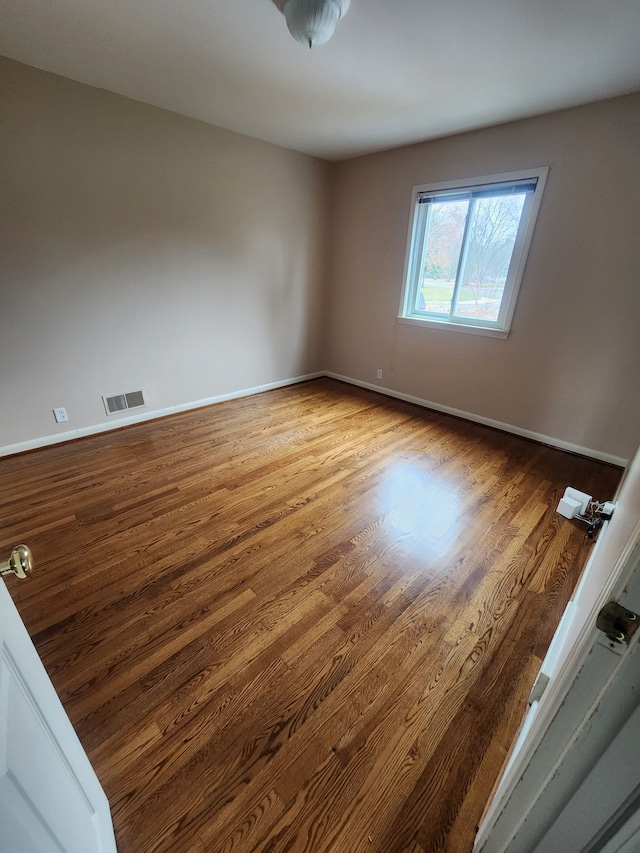 unfurnished room with visible vents, baseboards, and wood finished floors