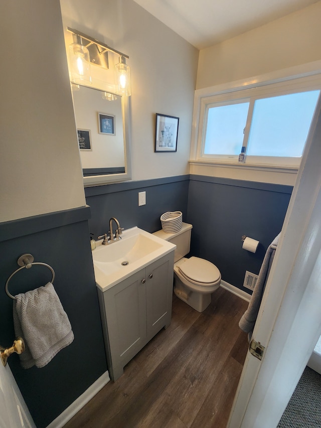 bathroom featuring toilet, wood finished floors, visible vents, vanity, and baseboards