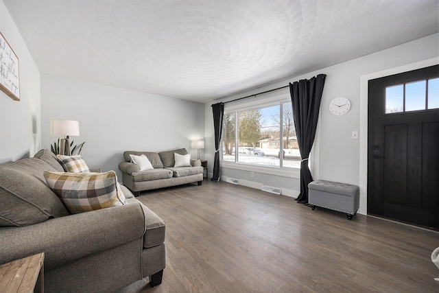 living area featuring visible vents, baseboards, and wood finished floors