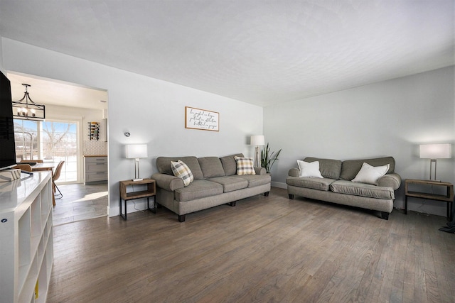 living room with an inviting chandelier, baseboards, and dark wood-style flooring