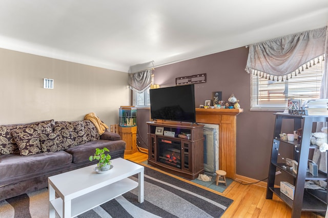 living area featuring a glass covered fireplace, wood finished floors, and visible vents