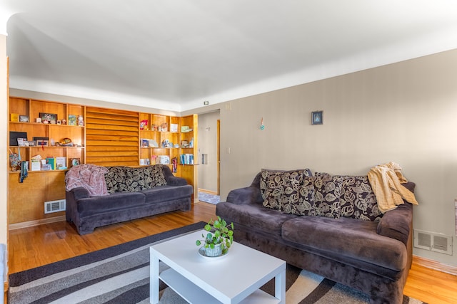 living area featuring built in features, baseboards, visible vents, and wood finished floors