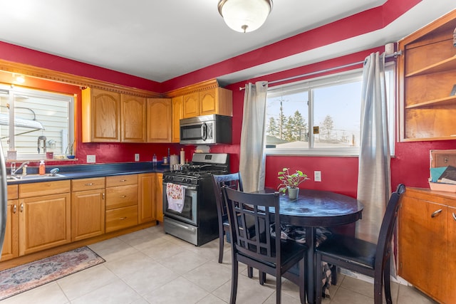 kitchen with dark countertops, appliances with stainless steel finishes, brown cabinetry, and a sink