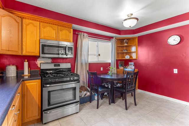 kitchen featuring appliances with stainless steel finishes, dark countertops, brown cabinetry, and baseboards