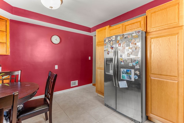 kitchen featuring light tile patterned flooring, stainless steel refrigerator with ice dispenser, visible vents, and baseboards