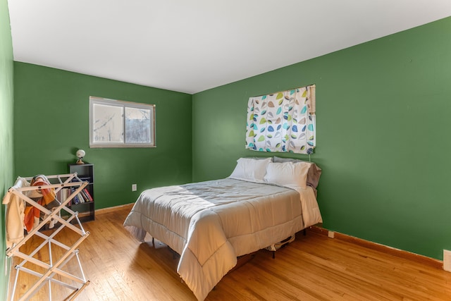 bedroom with wood-type flooring and baseboards