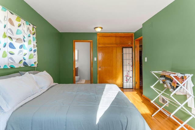 bedroom featuring ensuite bathroom and wood finished floors