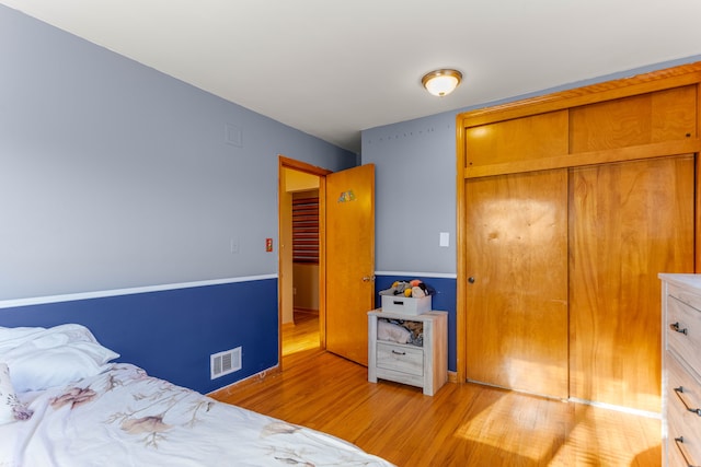 bedroom with light wood-type flooring, a closet, and visible vents