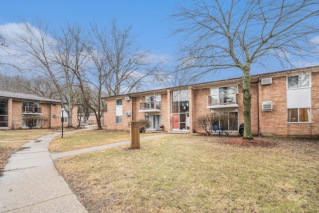 view of front facade featuring a front lawn, an AC wall unit, and brick siding