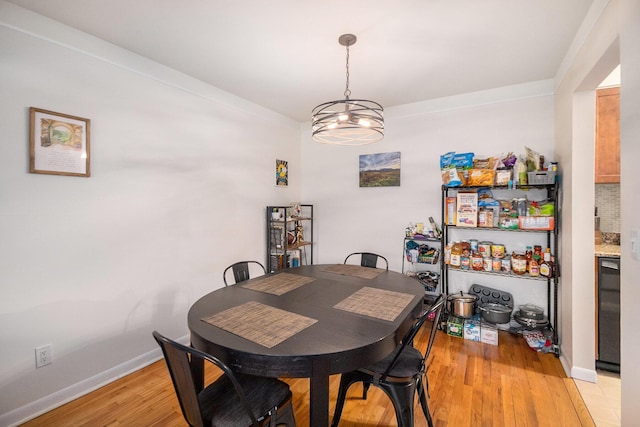 dining space with light wood finished floors, baseboards, and an inviting chandelier