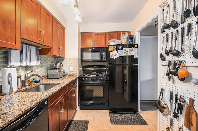 kitchen with decorative backsplash, brown cabinets, light stone countertops, black appliances, and a sink