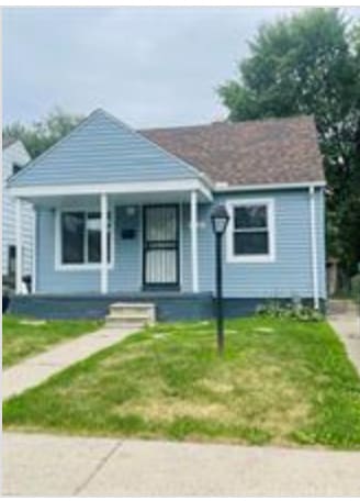 bungalow with covered porch and a front yard