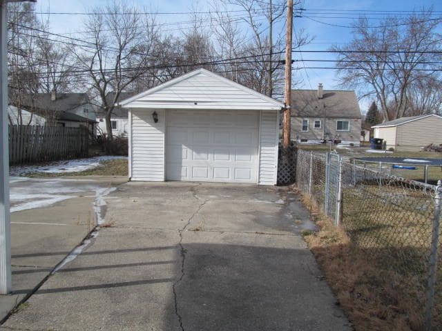 detached garage with fence and concrete driveway