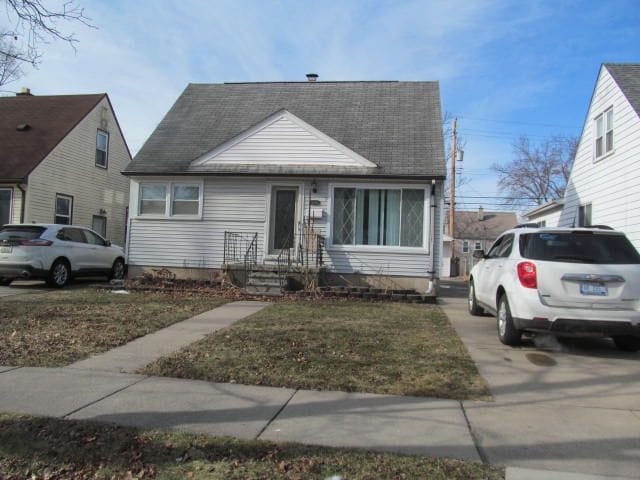 bungalow-style house with a front yard and roof with shingles