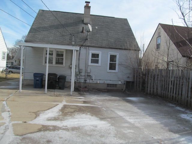 rear view of house featuring a shingled roof, fence, and a chimney