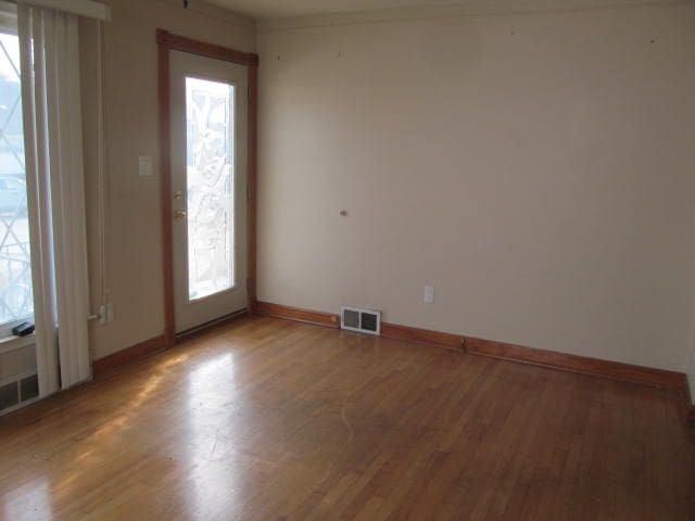 empty room featuring light wood-type flooring, visible vents, and baseboards