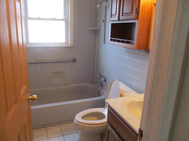 full bathroom featuring tile walls, toilet, tub / shower combination, vanity, and tile patterned flooring