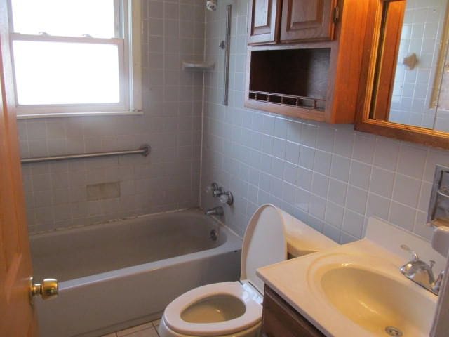 full bathroom featuring shower / bath combination, tasteful backsplash, toilet, vanity, and tile walls