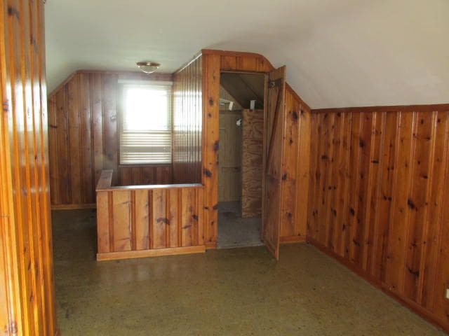 additional living space with vaulted ceiling and wood walls