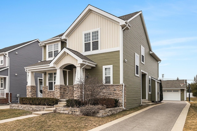 craftsman-style home with a garage, stone siding, an outdoor structure, a porch, and board and batten siding