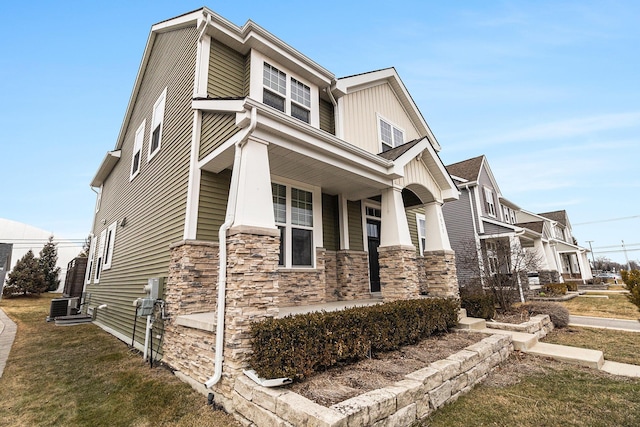 view of home's exterior featuring covered porch, stone siding, central AC unit, and a yard