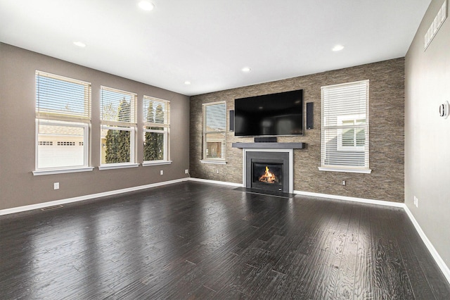 unfurnished living room with recessed lighting, visible vents, a fireplace with flush hearth, wood finished floors, and baseboards