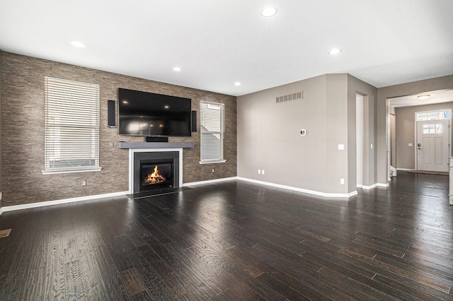 unfurnished living room featuring recessed lighting, wood finished floors, visible vents, baseboards, and a glass covered fireplace