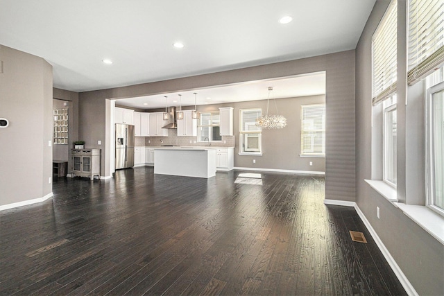 unfurnished living room with dark wood-style floors, baseboards, visible vents, and recessed lighting