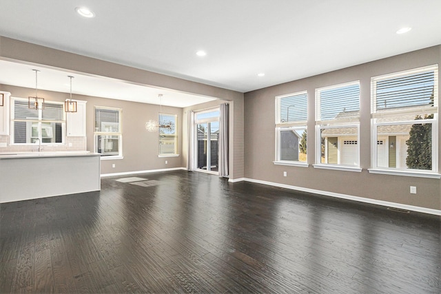 unfurnished living room featuring dark wood-type flooring, recessed lighting, and baseboards