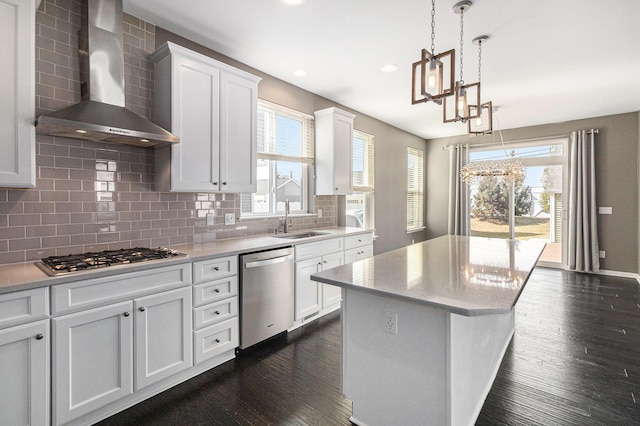 kitchen featuring stainless steel appliances, dark wood finished floors, a sink, and wall chimney range hood