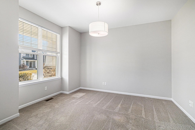 unfurnished room featuring carpet flooring, visible vents, and baseboards