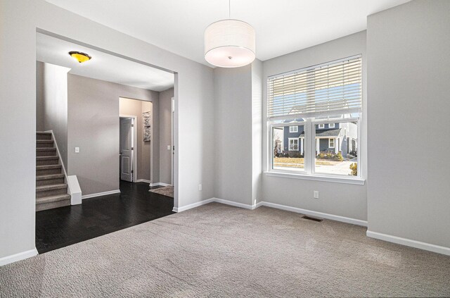 carpeted empty room with visible vents, baseboards, and stairs