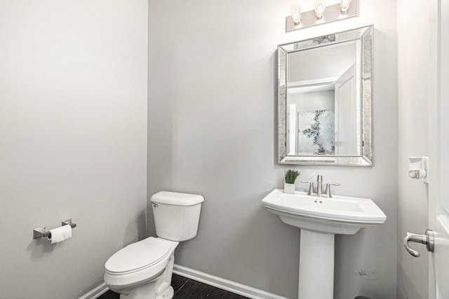 half bathroom with toilet, baseboards, and wood finished floors